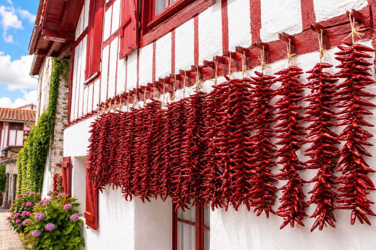 Cordes de piments d’Espelette rouges séchant sur une façade basque, épice AOP du Pays Basque